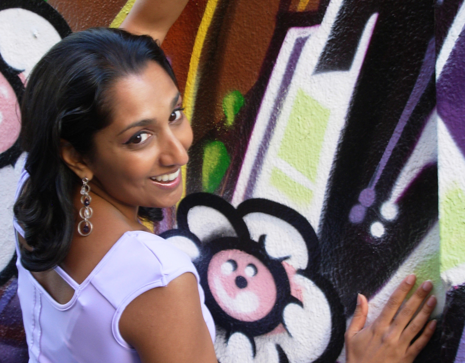 Headshot of Dhaya Lakshminarayanan in front of a colorful graffiti-style mural.
